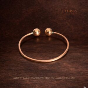 Pulsera artesanal de cobre con diseño abierto, estructura fina circular y esferas metálicas en los extremos, elegante y minimalista